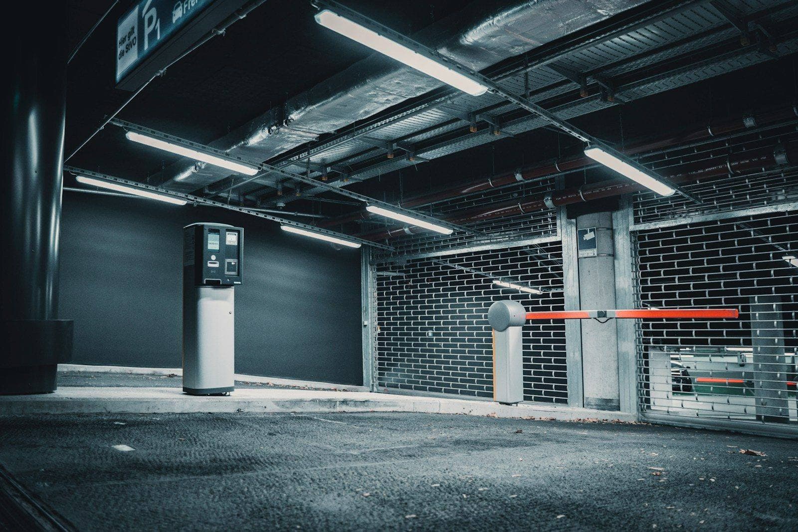 A parking garage pay station and barrier